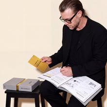 Julian Seidel arbeitet im Analyse-Dossier und hält die goldene Golden Rule Card Nr. 54