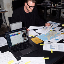 Julian Seidel am Analyse-Arbeitsplatz mit Videocall auf dem Laptop, Landkarte, SEO-Reports und Golden Rule Card