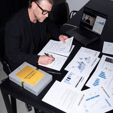 Julian Seidel notiert Ergebnisse auf Analyse-Ausdrucken, daneben GoldenRules Box mit Golden Rule Card und Laptop mit Videocall