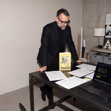 Dennis van Lierop am Arbeitstisch mit Notizen, Laptop und dem Buch Abgeschnitten