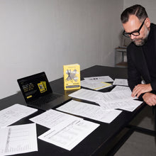 Arbeitstisch mit Manuskriptseiten, Laptop und dem Buch Abgeschnitten, Dennis van Lierop am Bildrand